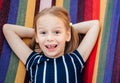 Happy little girl with crooked baby teeth in the colorful hammock summer background, summer holiday outdor activities Royalty Free Stock Photo