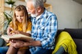 Happy little girl with grandfather reading story book at home