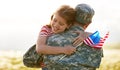 Happy girl daughter with american flag hugging father came back from US army