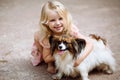 Happy little girl with a dog standing on the road in the park. Cute little girl hugging a dog, smiling. Child with dogs. Royalty Free Stock Photo