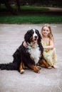 Happy little girl with a dog standing on the road in the park. Cute little girl hugging a dog, smiling. Child with dogs. Royalty Free Stock Photo