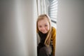 Happy little girl with Down syndrome sitting on window at home. Royalty Free Stock Photo