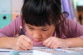 Happy little girl drawing with colored pencils on paper sitting at table in her room at home. Creativity and development of fine Royalty Free Stock Photo