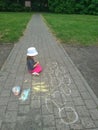 Happy little girl draws with colored crayons sitting on the sidewalk. Children draw with chalk on the street in the Park on the ro Royalty Free Stock Photo