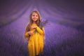 Happy little girl with dress enjoying lavender field with bouquet of flowers Royalty Free Stock Photo