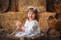 Happy little girl in a dress and wreath sits in a nest and holds a cute chicken Royalty Free Stock Photo