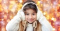 Happy little girl in earmuffs over holidays lights Royalty Free Stock Photo