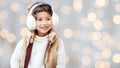 Happy little girl in earmuffs over holidays lights Royalty Free Stock Photo