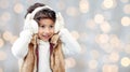 Happy little girl in earmuffs over holidays lights Royalty Free Stock Photo