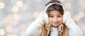 Happy little girl in earmuffs over holidays lights Royalty Free Stock Photo