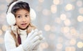 Happy little girl in earmuffs over holidays lights Royalty Free Stock Photo