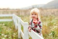 Happy little girl eating apple outdoors. Cute child girl on a walk on a farm. Girl with amazing eyes and blonde hair. Healthy food Royalty Free Stock Photo