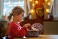 Happy little girl eating gingerbread Christmas cookies in domestic kitchen decorated with lights. Cute school child with Royalty Free Stock Photo