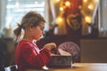 Happy little girl eating gingerbread Christmas cookies in domestic kitchen decorated with lights. Cute school child with Royalty Free Stock Photo