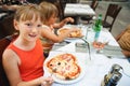 Happy little girl eating kid`s pizza in the restaurant Royalty Free Stock Photo