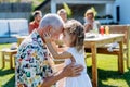 Happy little girl embracing her grandfather at generation family birthday party in summer garden. Royalty Free Stock Photo