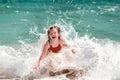Happy little girl enjoying sea waves. Child playing in the sea. Kid in swimming suit having fun on the sand beach Royalty Free Stock Photo