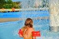 Happy little girl enjoying summer day in the swimming pool. Girl going to a sprinkler in spray pool. Cute girl with inflatable ar Royalty Free Stock Photo