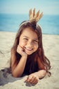 Happy little girl enjoying sunny day at the beach.Wearing a princess crown