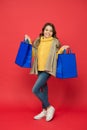 Happy little girl with fashion look carry shopping bags red background, sale Royalty Free Stock Photo