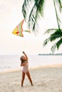 Happy little girl with flying kite on tropical beach under palm tree Royalty Free Stock Photo