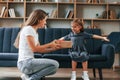 Happy little girl is with gift box. Young mother with her daughter is together at apartment Royalty Free Stock Photo