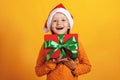 Happy little girl with a gift for Christmas. A child in a santa hat holds a box with a present Royalty Free Stock Photo