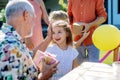 Happy little girl giving birthday present to her senior grandfather at generation family birthday party in summer garden Royalty Free Stock Photo