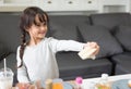 Happy little girl giving sandwich cooking toy as chef in living room. Playful of child and happiness education and development