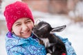 Happy Little Girl With Goatling In Village In Winter Close-Up