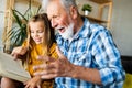 Happy little girl with grandfather reading story book at home Royalty Free Stock Photo