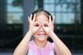 Happy little girl with hands glasses in front of her eyes