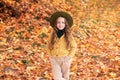 Happy little girl in hat and autumn clothes on an autumn background. A smiling child is playing in fall park. Royalty Free Stock Photo