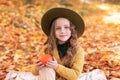 Happy little girl in hat and autumn clothes on an autumn background. A smiling child is playing in fall park. Royalty Free Stock Photo