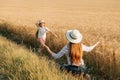 happy little girl with hat on her head runs to her mother next to a wheat field Royalty Free Stock Photo