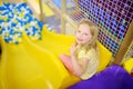 Happy little girl having fun in ball pit in kids indoor play center. Child playing with colorful balls in playground ball pool. Royalty Free Stock Photo