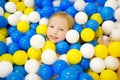 Happy little girl having fun in ball pit in kids indoor play center. Child playing with colorful balls in playground ball pool. Royalty Free Stock Photo