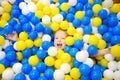 Happy little girl having fun in ball pit in kids indoor play center. Child playing with colorful balls in playground ball pool. Royalty Free Stock Photo