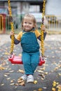 Happy little girl having fun on outdoor playground. Swinging on swing