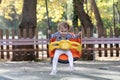 Happy little girl having fun on outdoor playground. Swinging on swing