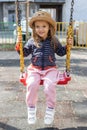 Happy little girl having fun on outdoor playground. Swinging on swing