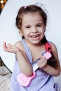 Happy little girl having fun playing with toy guitar or ukulele. Royalty Free Stock Photo