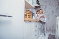Happy little girl and her beautiful young mother have breakfast together in a white kitchen. They hug and drink tea. Maternal care Royalty Free Stock Photo