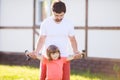 Happy little girl and her father lifting dumbbells outdoors