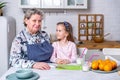 Happy little girl and her grandmother have breakfast together in a white kitchen. They are having fun and playing with fruits. Royalty Free Stock Photo