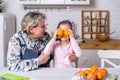 Happy little girl and her grandmother have breakfast together in a white kitchen. They are having fun and playing with fruits. Royalty Free Stock Photo