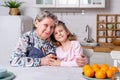 Happy little girl and her grandmother have breakfast together in a white kitchen. They are having fun and playing with fruits. Royalty Free Stock Photo