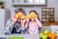 Happy little girl and her grandmother have breakfast together in a white kitchen. They are having fun and playing with fruits. Royalty Free Stock Photo