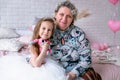 Happy little girl and her grandmother are sitting together and hugging in the bedroom. They are smilling and kissing. Maternal Royalty Free Stock Photo