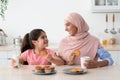 Happy Little Girl And Her Islamic Mom Having Snacks In Kitchen Together Royalty Free Stock Photo